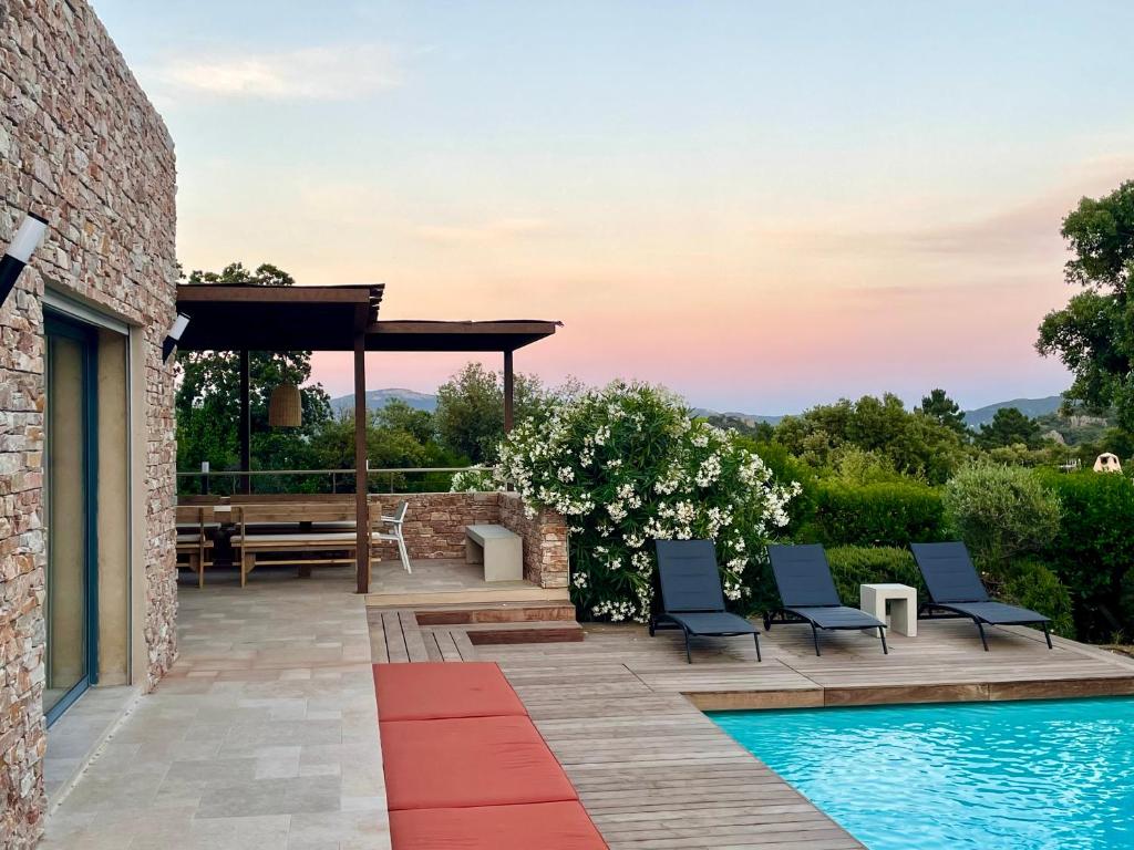 taras ze stołem i krzesłami obok basenu w obiekcie Villa Terra Vecchia, 6 ou 12 personnes, vue imprenable, piscine chauffée w mieście Porto-Vecchio
