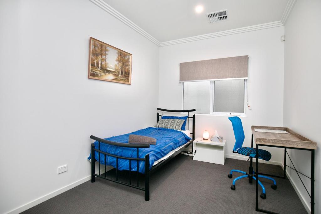a bedroom with a blue bed and a desk and a chair at Private room single bed close to beach 7min in Oaklands