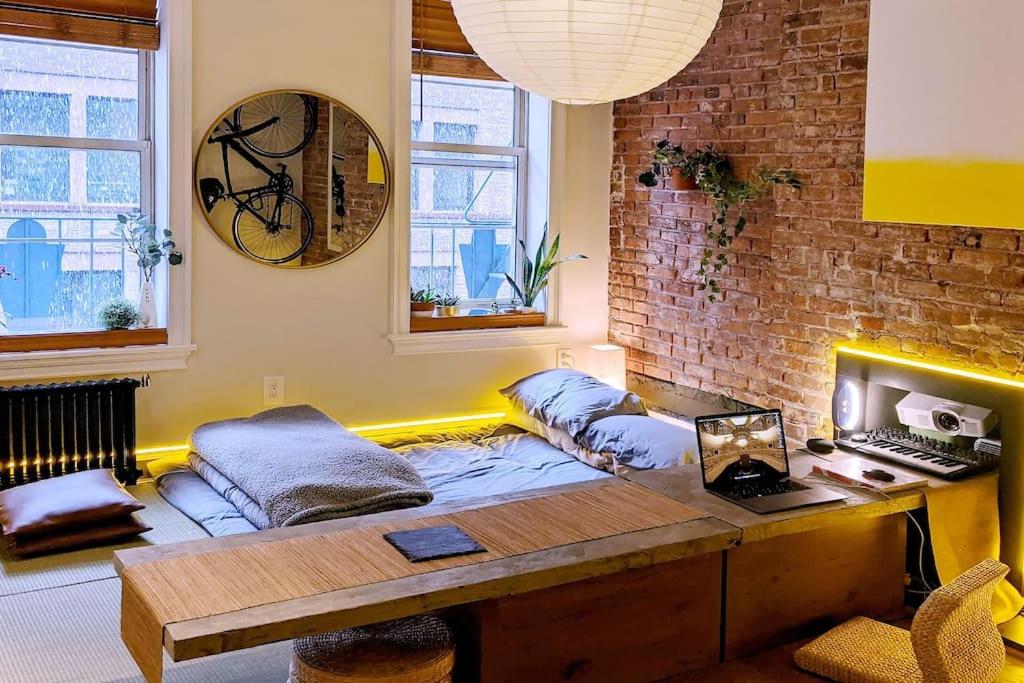 a room with a couch and a desk and a brick wall at Peaceful Japanese Ryokan in the heart West Village in New York