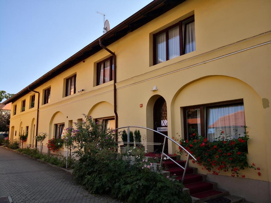 a yellow building with stairs and flowers in front of it at Grand Bells Bed And Breakfast in Zagreb