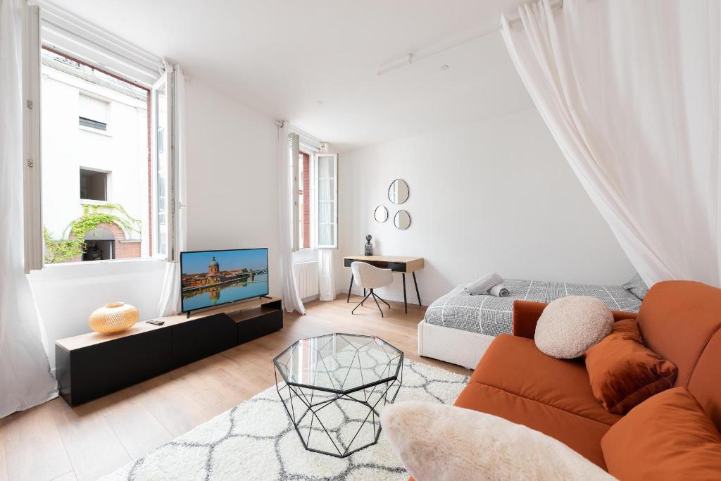 uma sala de estar branca com um sofá e uma televisão em Appartement moderne à 2 pas de la Gare em Toulouse