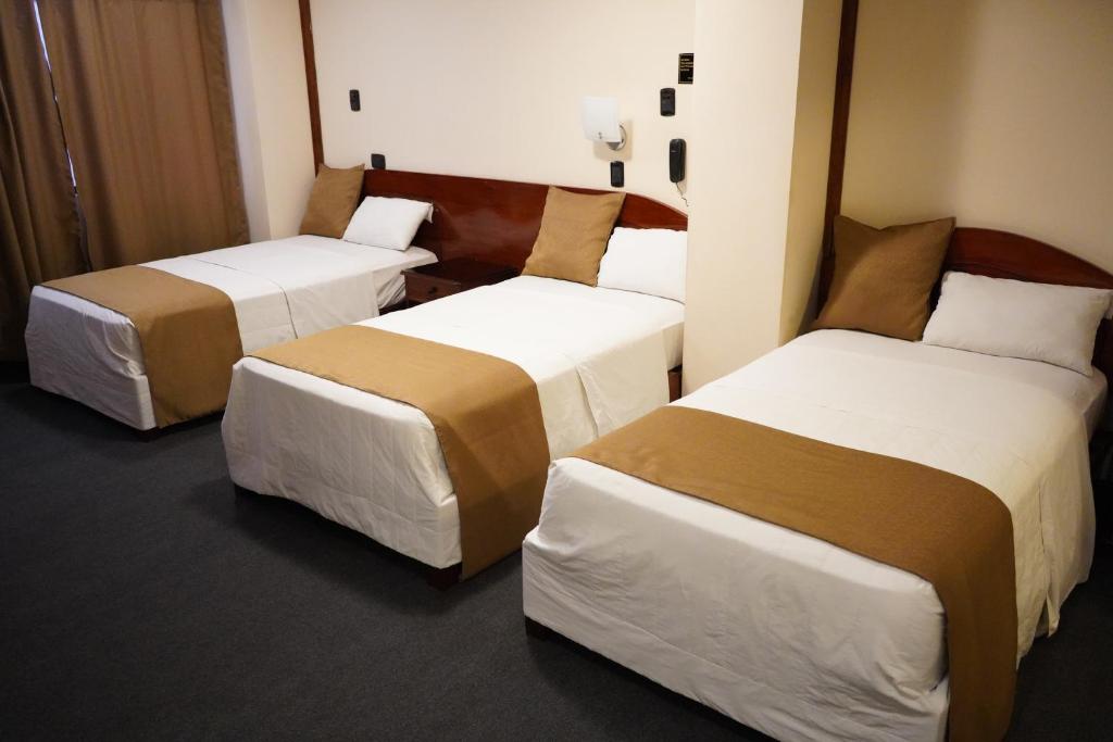 a room with three beds in a hotel room at Amara Hotel in Lima