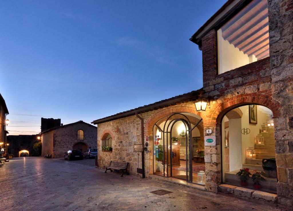 ein Steingebäude mit einer Bank in einer Straße in der Unterkunft Romantik Hotel Monteriggioni in Monteriggioni