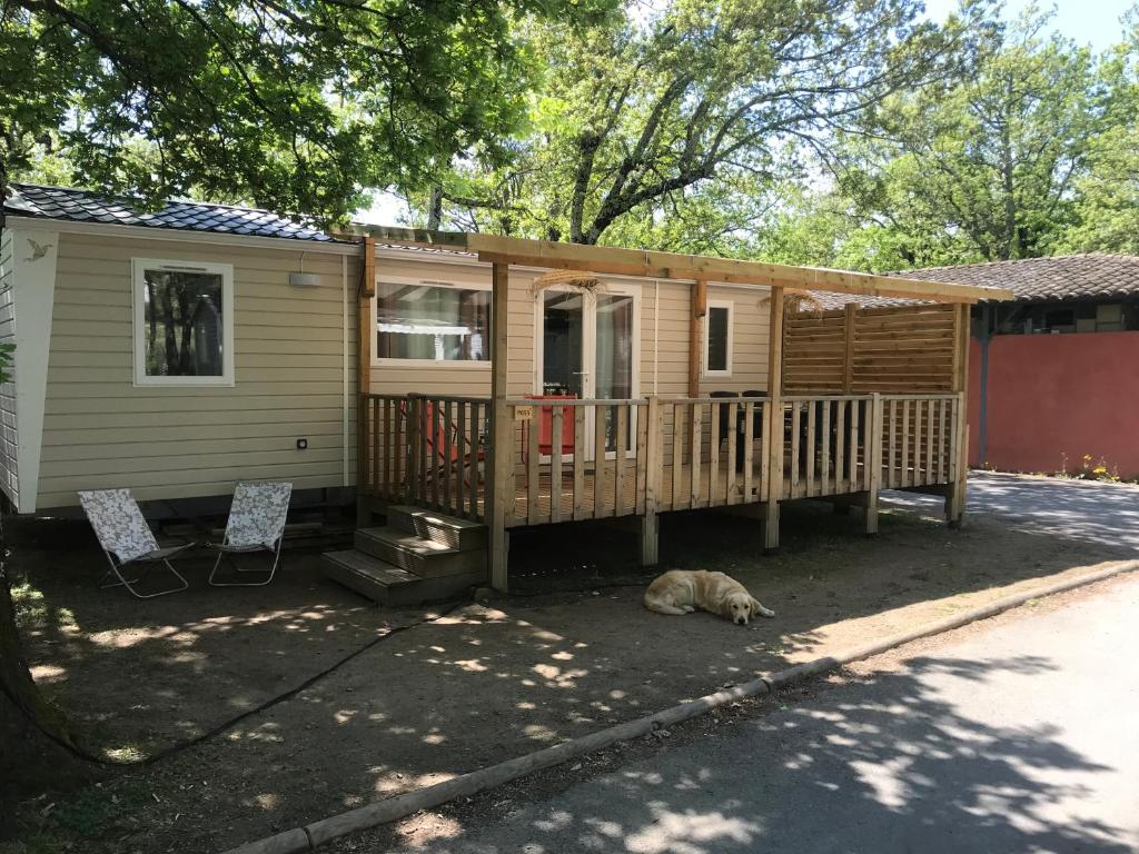 a cabin with a deck and a cat laying on the ground at Chaussy55 in Lagorce