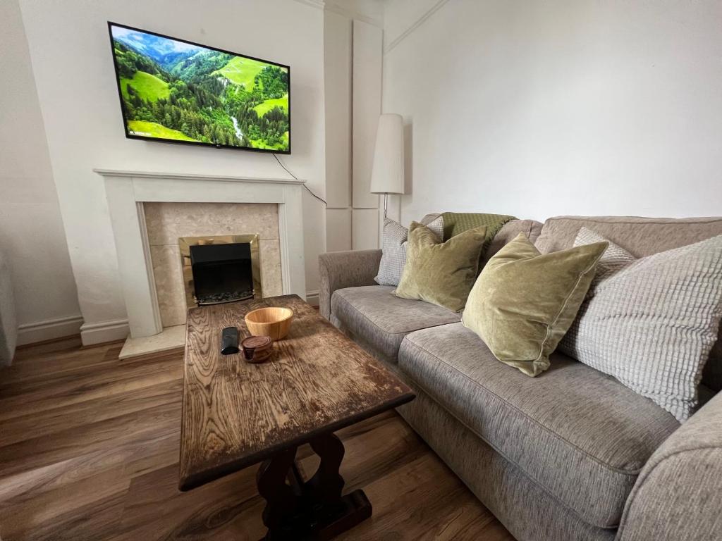 a living room with a couch and a tv on the wall at Liverpool Ivy House - 4 Bedrooms in Liverpool