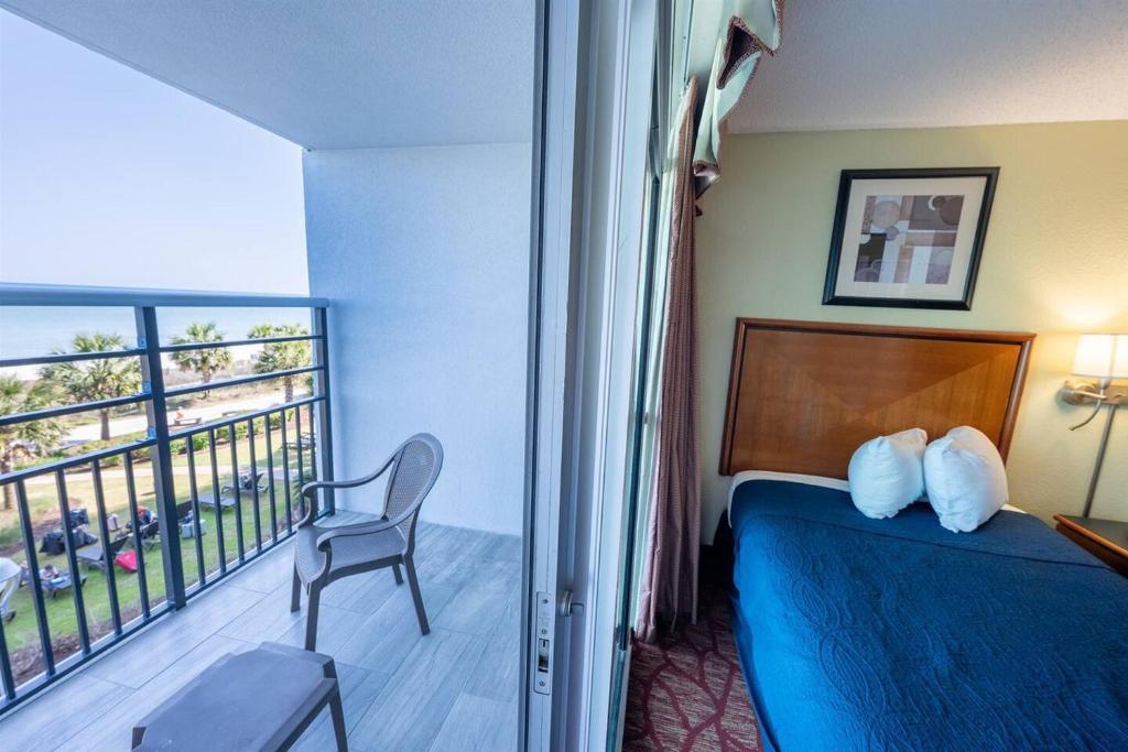 a hotel room with a bed and a balcony at Low Floor,Direct Oceanfront,Heated Pool,Boardwalk! in Myrtle Beach