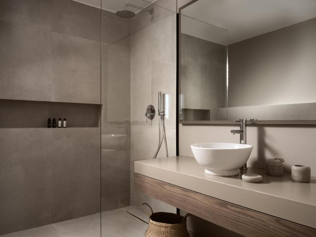 a bathroom with a sink and a glass shower at The Bay Hotel & Suites in Vasilikos