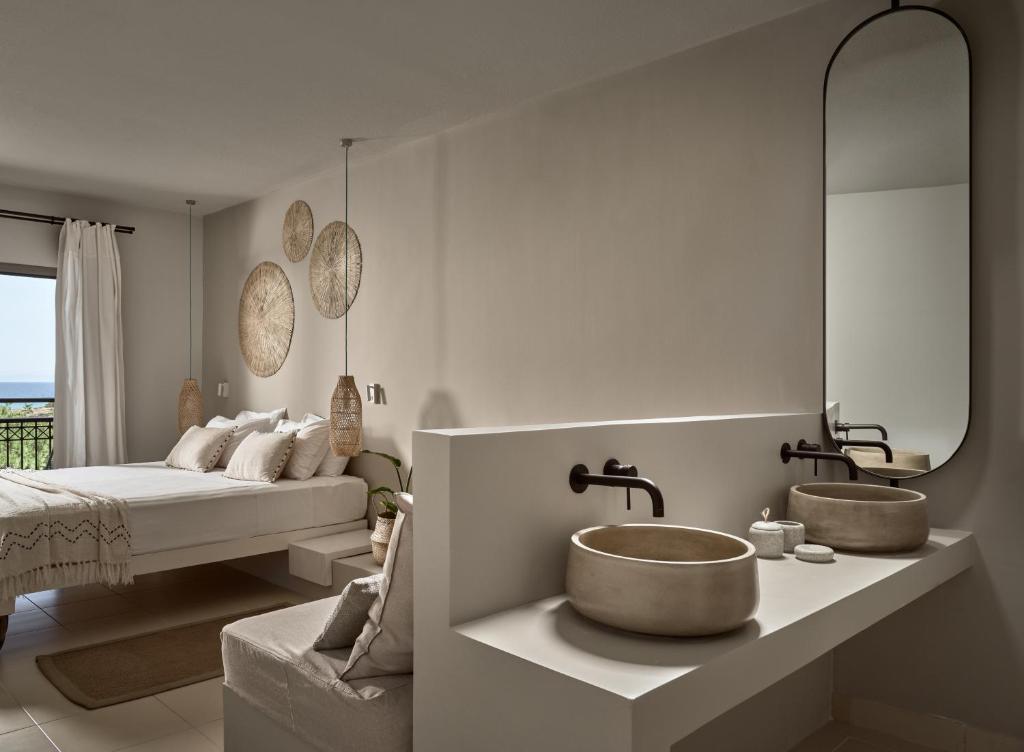 a bathroom with two sinks and a bed at The Bay Hotel & Suites in Vasilikos