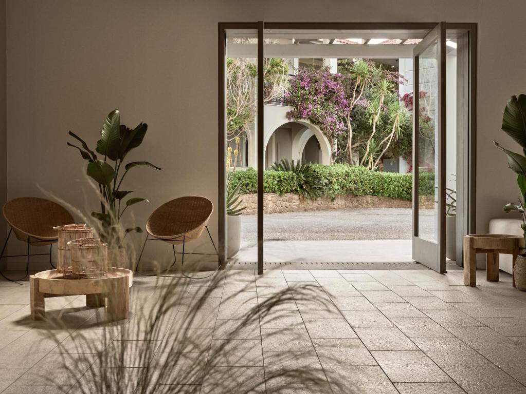 an open door to a patio with chairs and a table at The Bay Hotel & Suites in Vasilikos