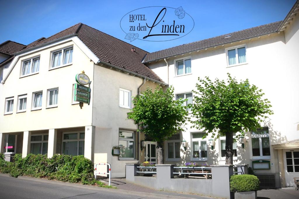 a white building with trees in front of it at Hotel zu den Linden in Wachtberg