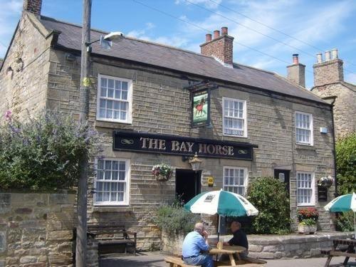 dos personas sentadas en una mesa frente a la casa de la bahía en The Bay Horse Country Inn en Thirsk