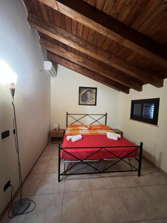 una camera con letto rosso e soffitto in legno di Casa vacanze Arianna a Noto Marina