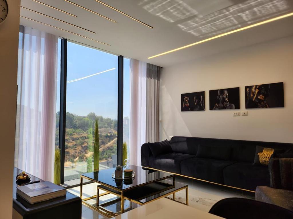 3BR Luxury Suite in Jerusalem في القدس: غرفة معيشة مع أريكة سوداء ونافذة كبيرة