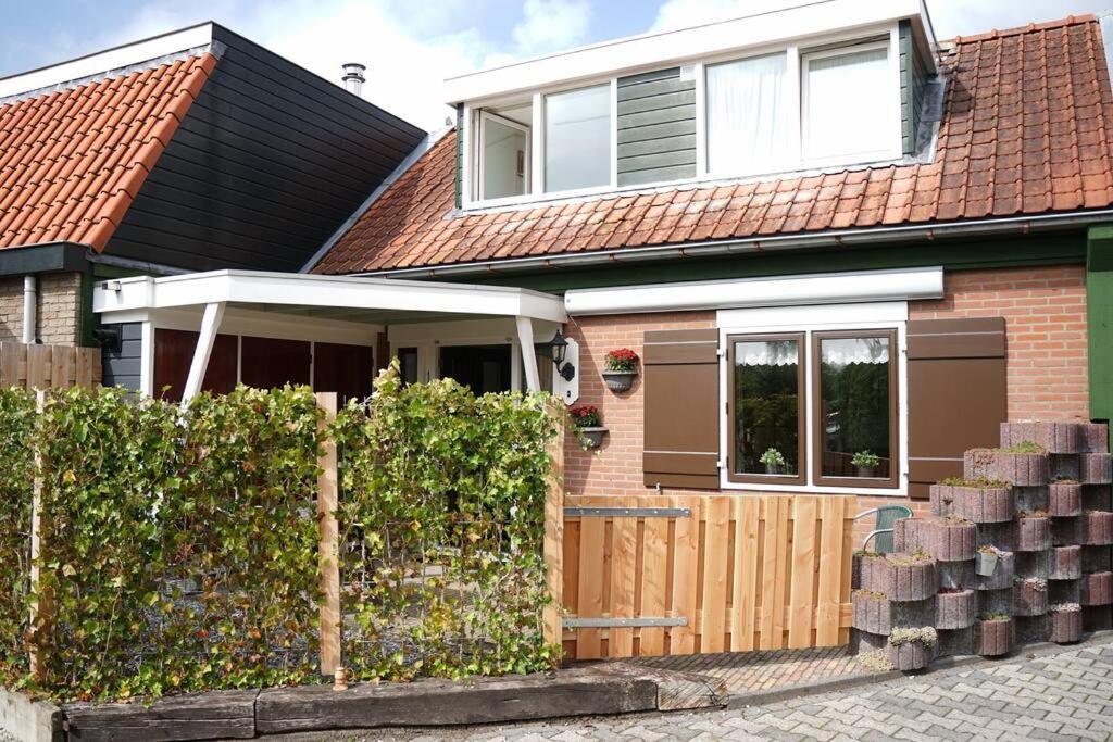 une maison avec une porte en bois et une clôture dans l'établissement Huisje Marie Loosdrecht, à Loosdrecht