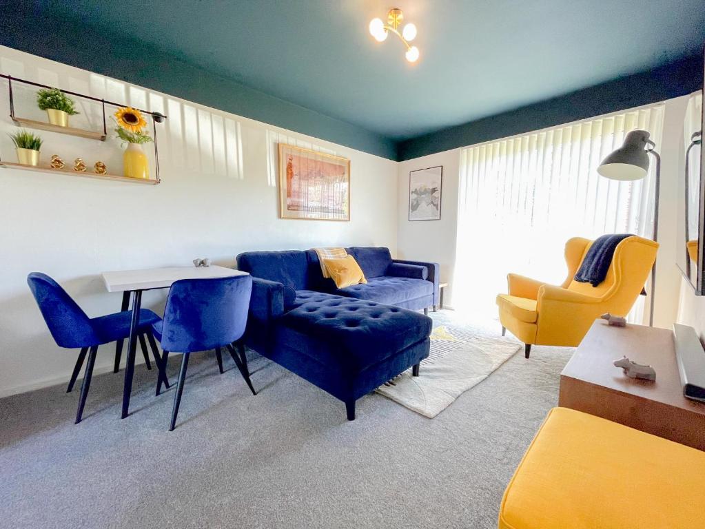 uma sala de estar com um sofá azul e uma mesa e cadeiras em Escape to Tranquil 1 bed, Poole em Canford Magna