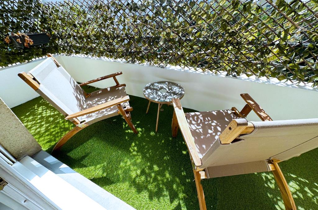 een patio met een stoel en een tafel op het gras bij L'écrin du stade By UTA HOUSE in Saint-Denis