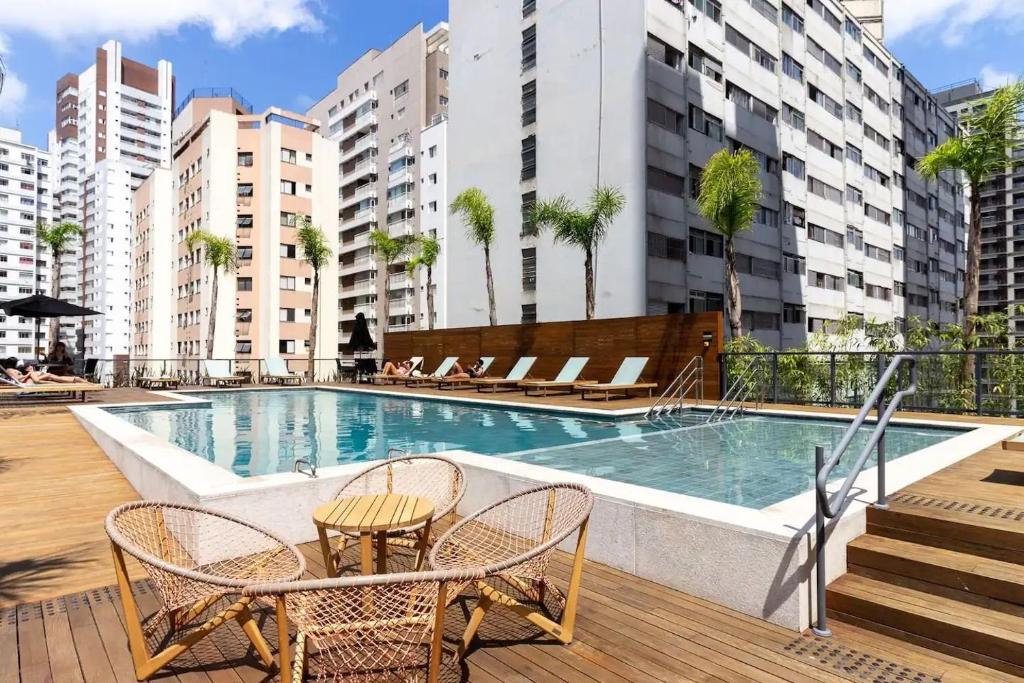 a swimming pool with chairs and tables in a building at Apartamento na paulista (com garagem) in Sao Paulo