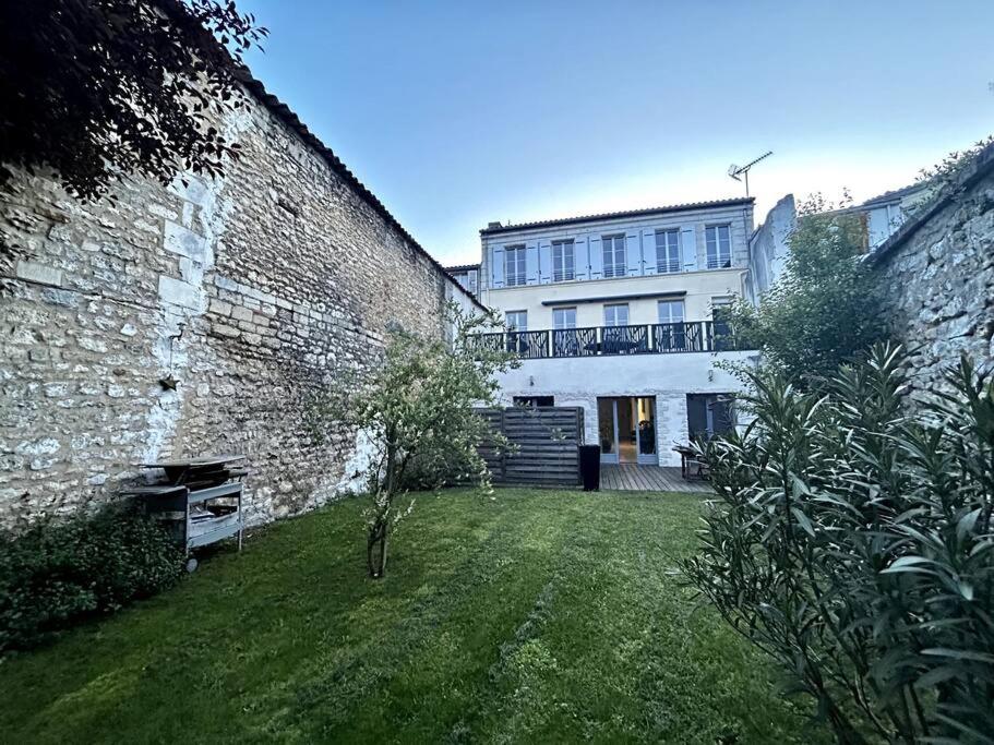 a large brick building with a yard next to a building at Logements situés en plein cœur de ville avec jardin in Rochefort