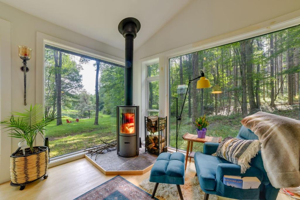 sala de estar con chimenea frente a una ventana en Secluded Upstate NY Forest Cottage on 33 Acres! en Oneonta