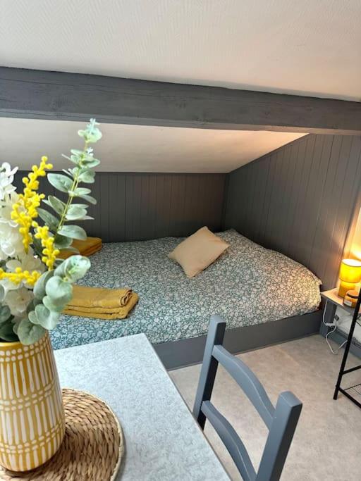 Cette chambre comprend un lit et une table avec un vase de fleurs. dans l'établissement Studio proche Gare, à Bourg-en-Bresse