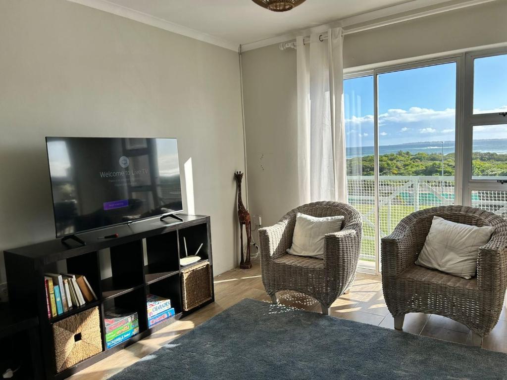 een woonkamer met 2 stoelen en een flatscreen-tv bij Bella Casa - Seaview-Beach Club Apartment in Kaapstad