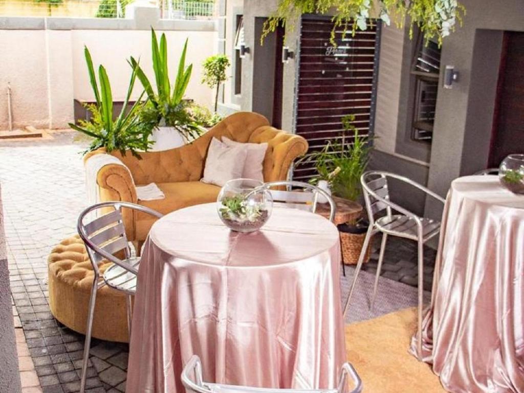 a patio with two tables and chairs and a couch at @ 21 Guest House in Pietermaritzburg