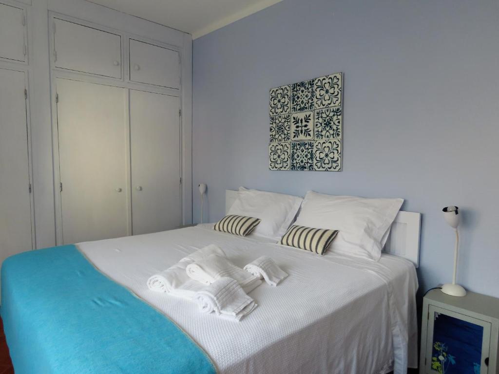 een slaapkamer met een wit bed en handdoeken bij Casa do Portão Azul - Espadarte in Atouguia da Baleia