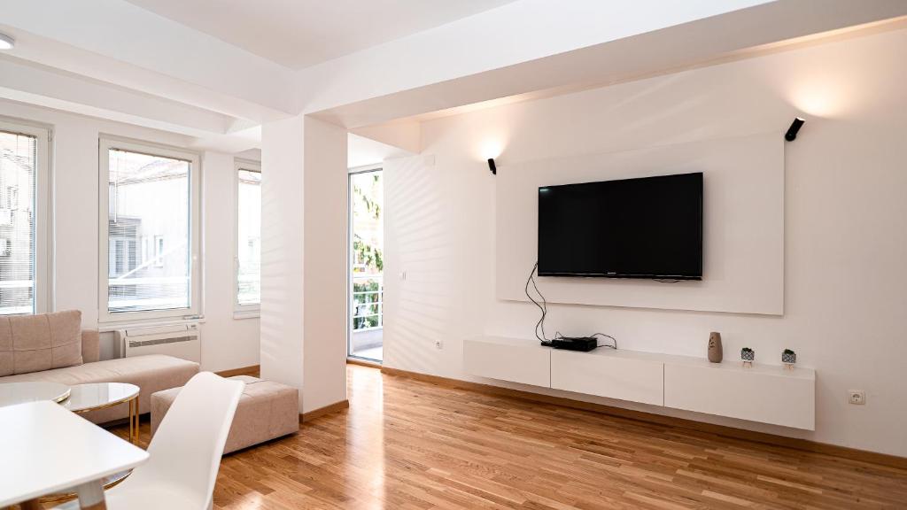 a white living room with a flat screen tv on a wall at Golden Apartment in Skopje