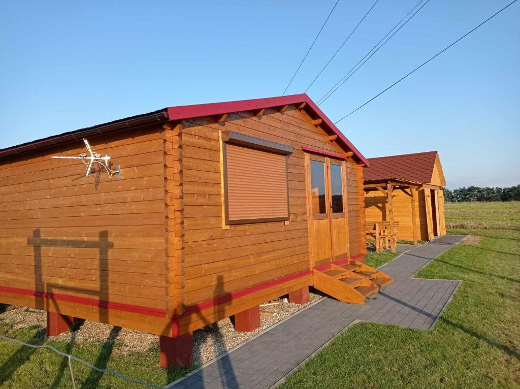 a wooden cabin in a field of grass at Domek pod gwiazdami z jacuzzi in Brzozowa