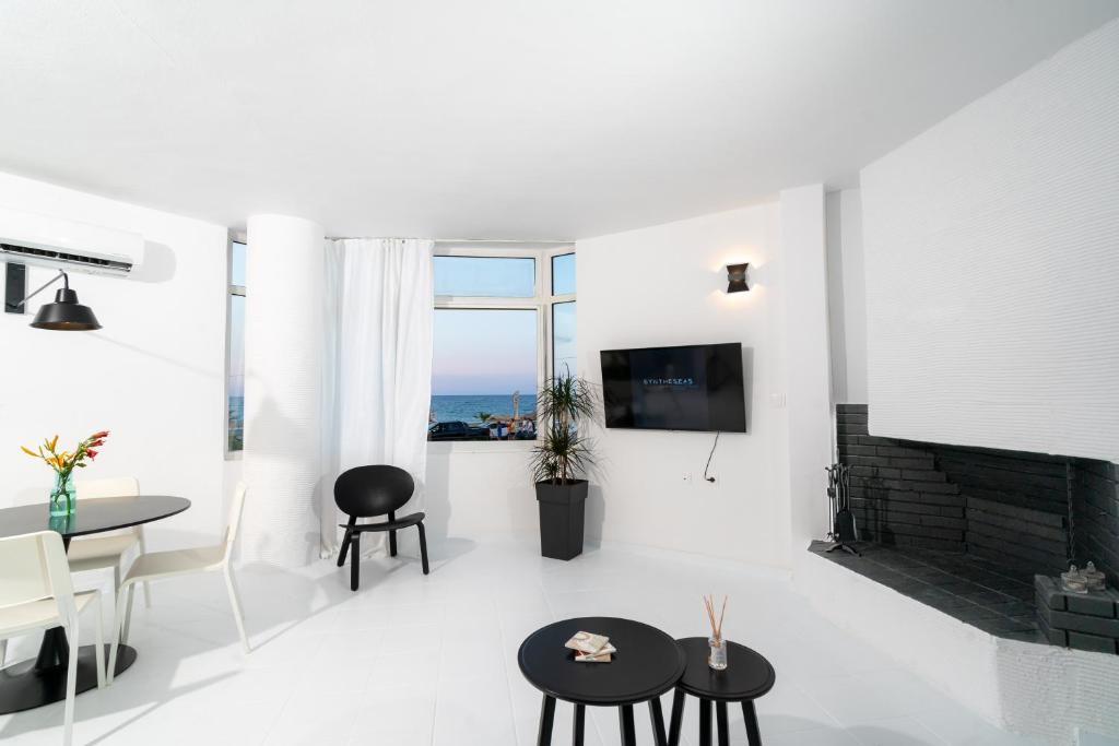 sala de estar blanca con chimenea y mesa en SyntheSeas Residence, en Rethymno