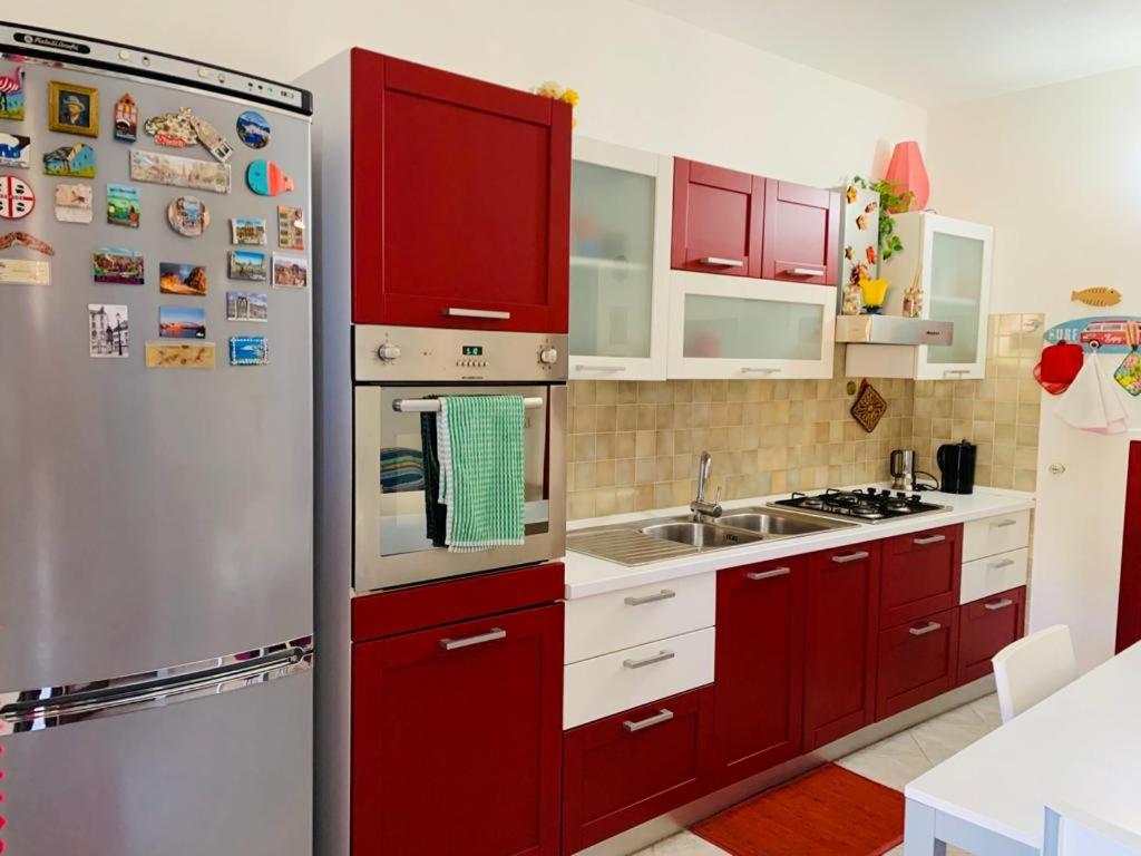 eine Küche mit roten Schränken und einem Kühlschrank aus Edelstahl in der Unterkunft Valledoria Residenza sole e mare in Codaruina