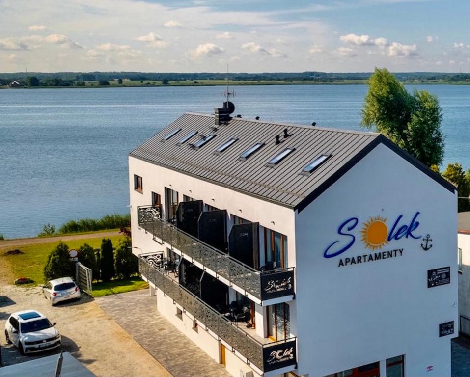 梅爾諾的住宿－SOLEK Apartamenty i pokoje gościnne，水边屋顶上有太阳的建筑
