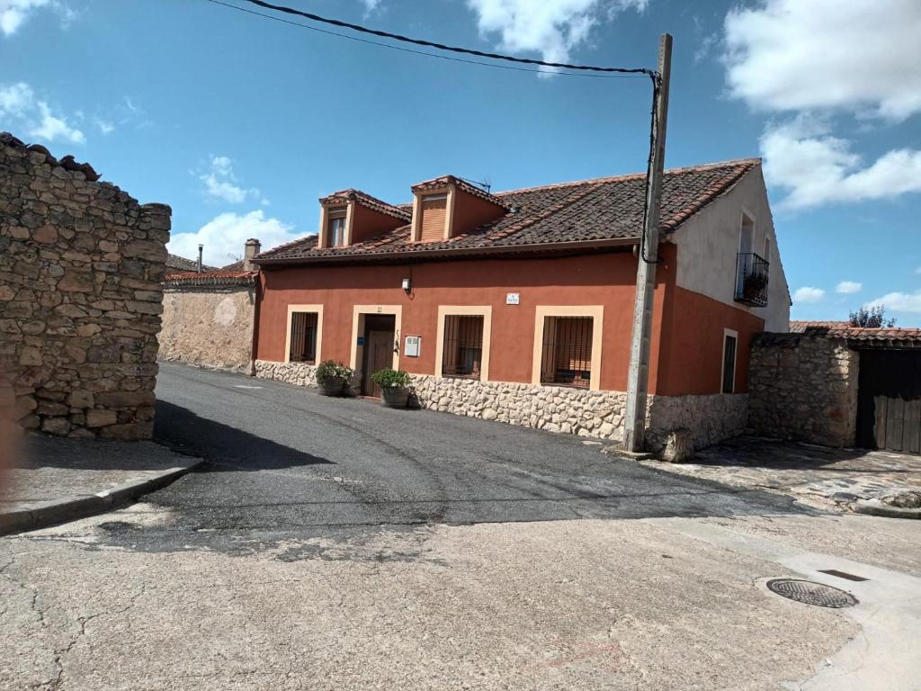 a red and white house with a stone wall at El Refugio de la Esquina in Mata de Quintanar