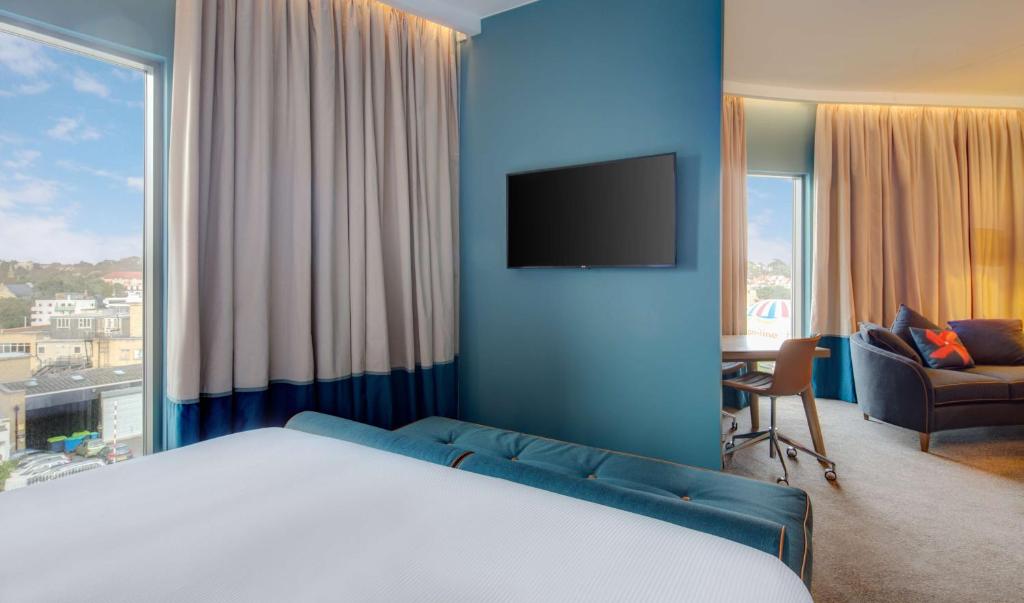 a bedroom with a bed and a tv and a couch at Hilton Bournemouth in Bournemouth