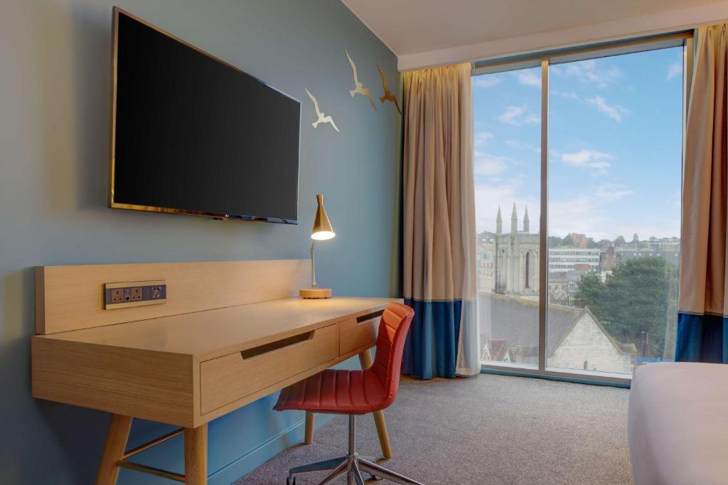 a room with a desk with a tv and a window at Hilton Bournemouth in Bournemouth