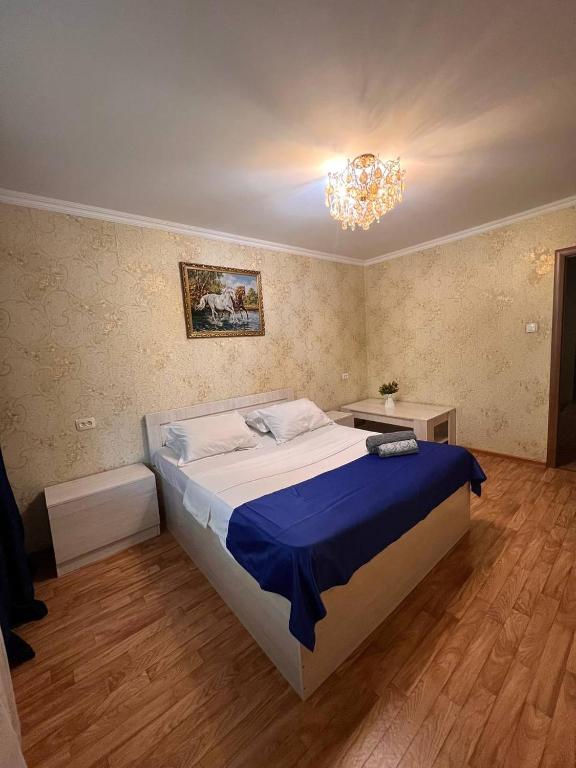 Un dormitorio con una cama grande y una lámpara de araña. en Апартаменты на Mege, en Shymkent