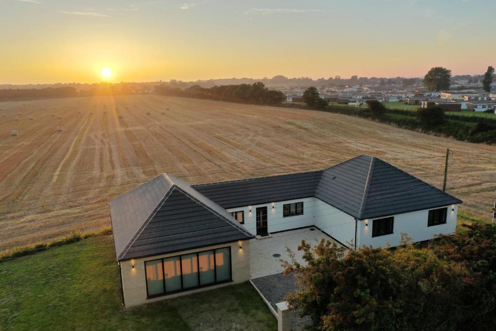 a house in a field with the sunset in the background at Metfield in Great Yarmouth