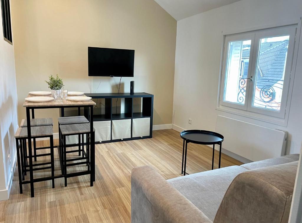 - un salon avec une télévision, une table et des chaises dans l'établissement Le Cocon - logement 4 personnes - Neuf - Wifi, au Bourget