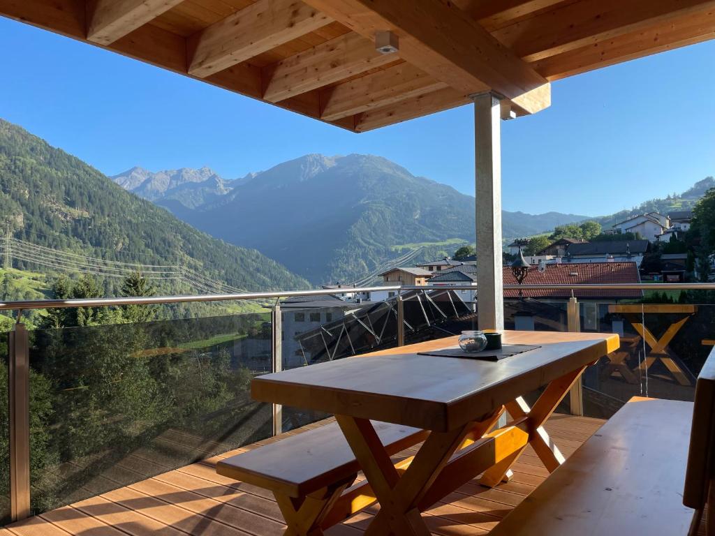 a wooden table on a deck with a view of mountains at Apart Finazzer in Wenns