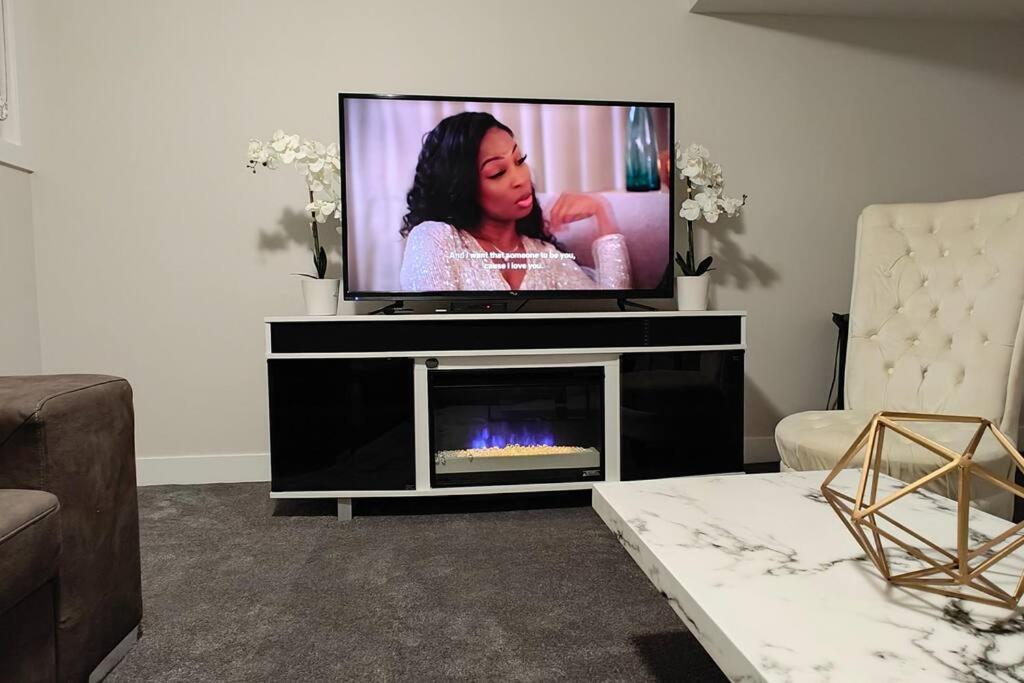 einen Flachbild-TV im Wohnzimmer mit Kamin in der Unterkunft BlissfulAbode Basement Suite in Airdrie