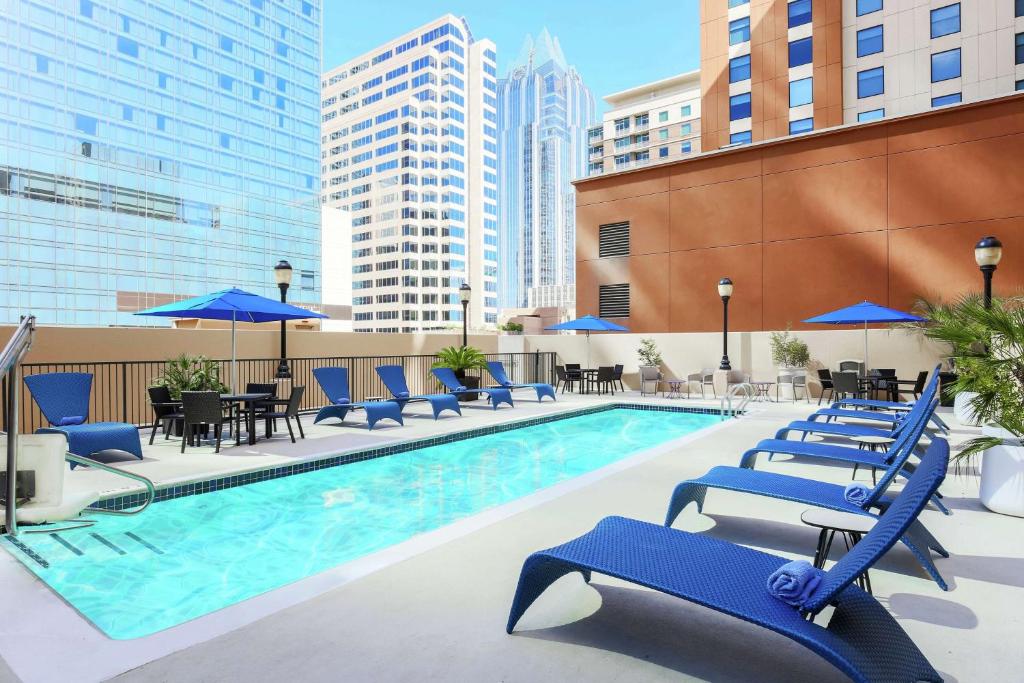 una piscina con sillas azules, mesas y sombrillas en Hampton Inn & Suites Austin-Downtown/Convention Center, en Austin