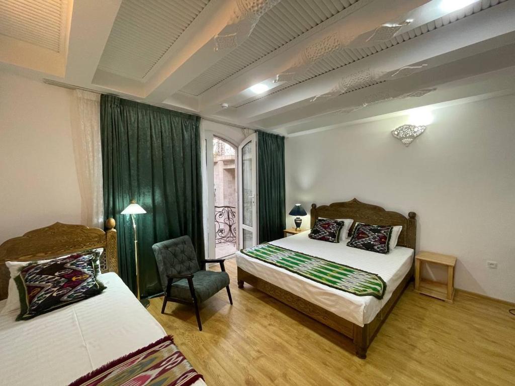 een slaapkamer met 2 bedden, een stoel en een raam bij Prestige Terrace Hotel in Bukhara