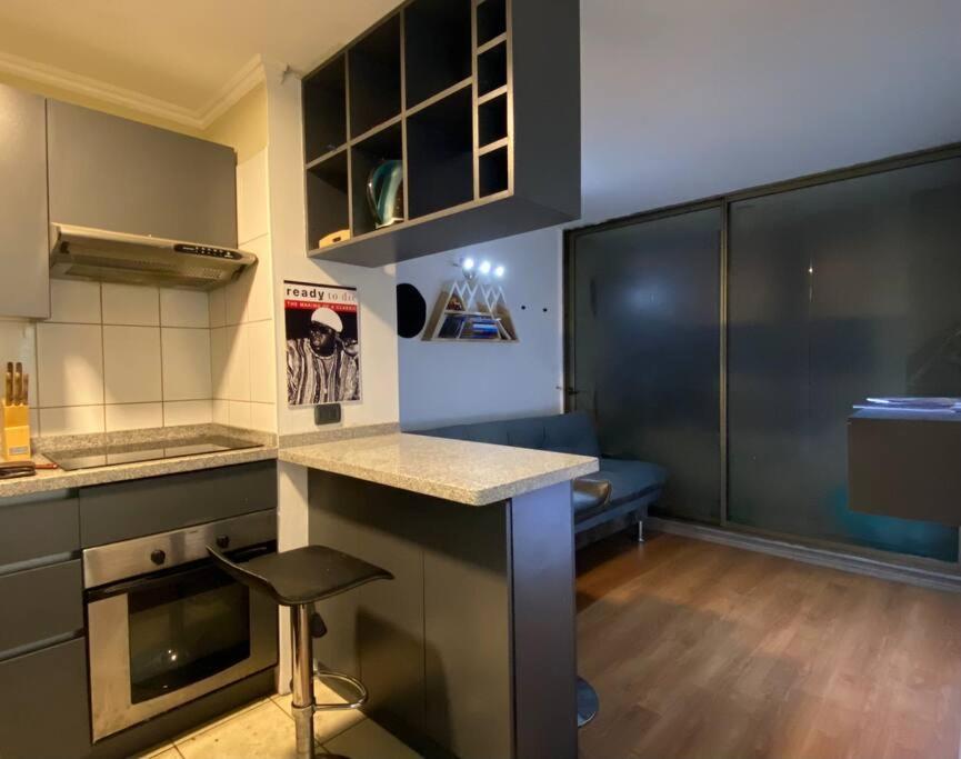 a kitchen with a counter and a couch in a room at Apartamento centro Santiago vacaciones trabajo in Santiago