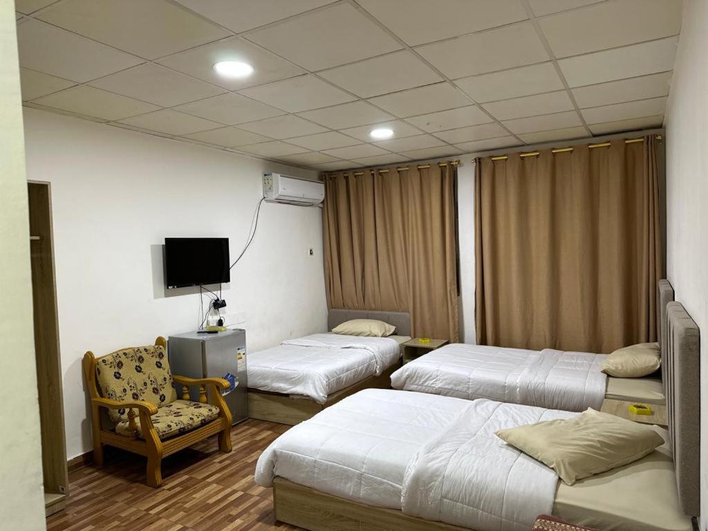 Cette chambre comprend 3 lits, une chaise et une télévision. dans l'établissement فندق الروان, 