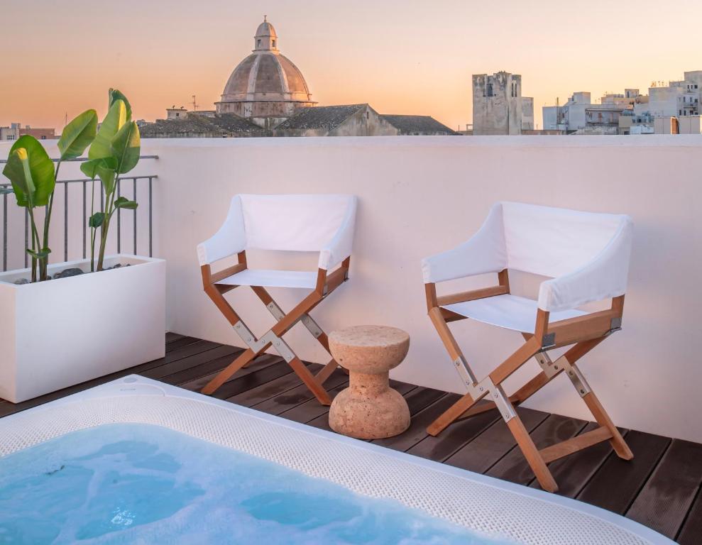 two chairs and a swimming pool on a balcony at WeLive Trapani - luxury apartments in Trapani