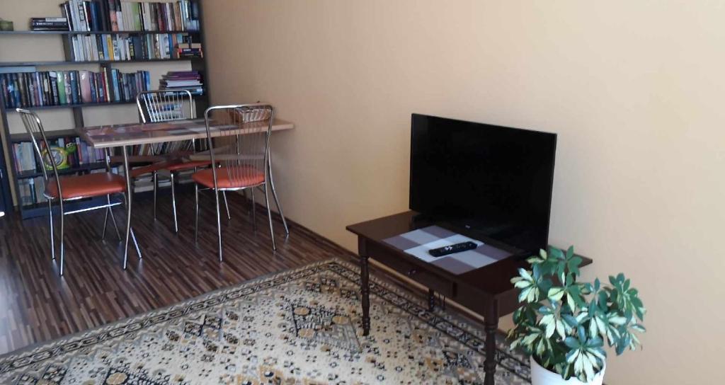 a living room with a tv and a table and chairs at Centrinio parko apartamentai in Šiauliai