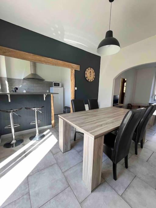 a dining room with a wooden table and black chairs at Maison calme à proximité des 3 frontières in Longuyon