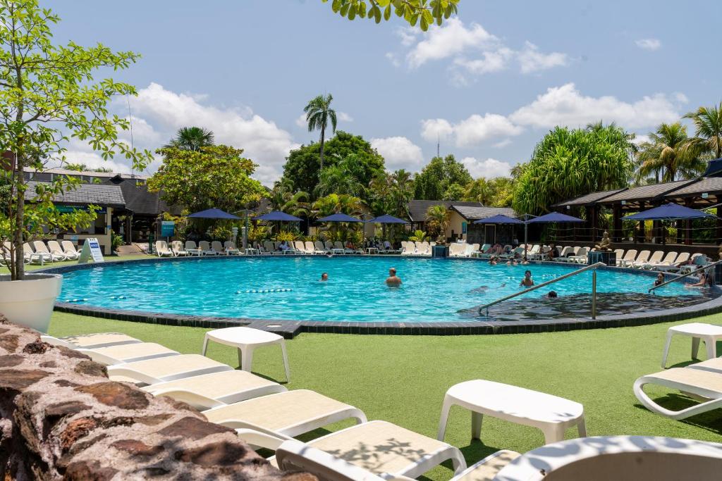 uma grande piscina com cadeiras brancas e pessoas nela em Torarica Resort em Paramaribo