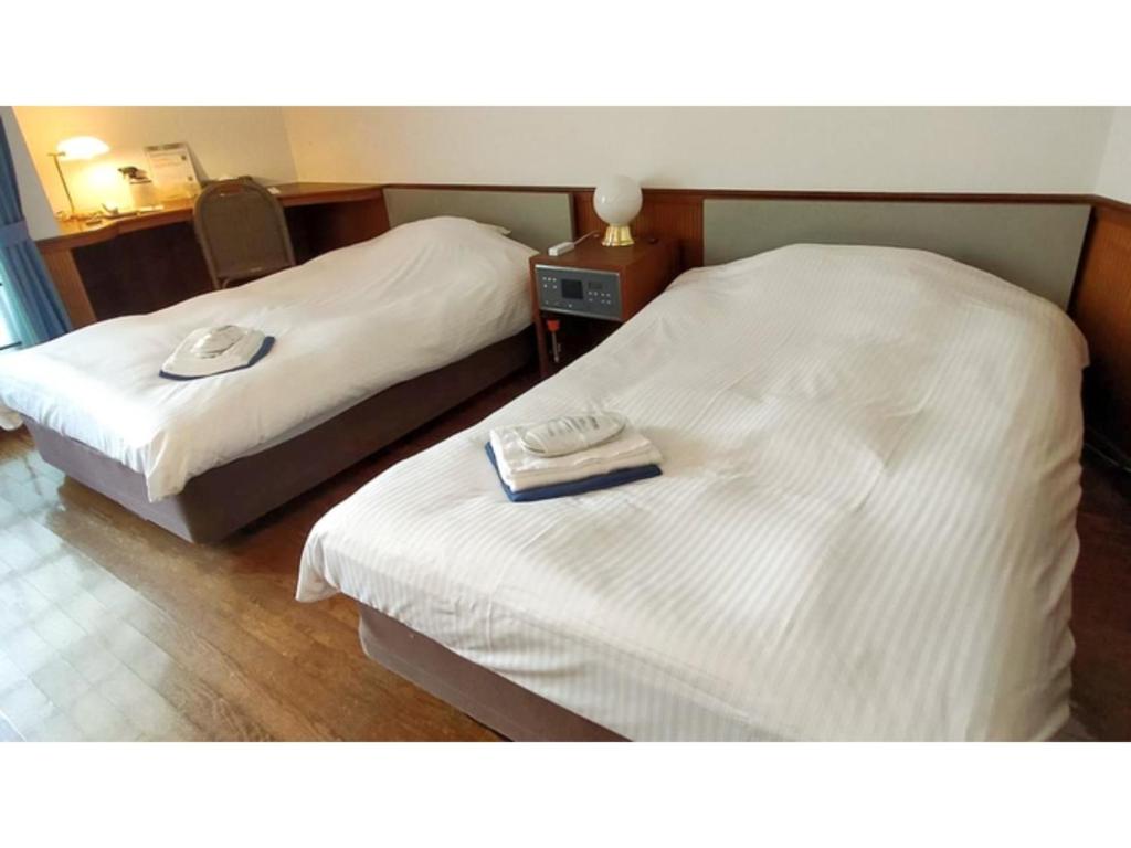 two beds in a hotel room with towels on them at ＨＯＴＥＬ ＰＯＳＨ - Vacation STAY 55613v in Odawara