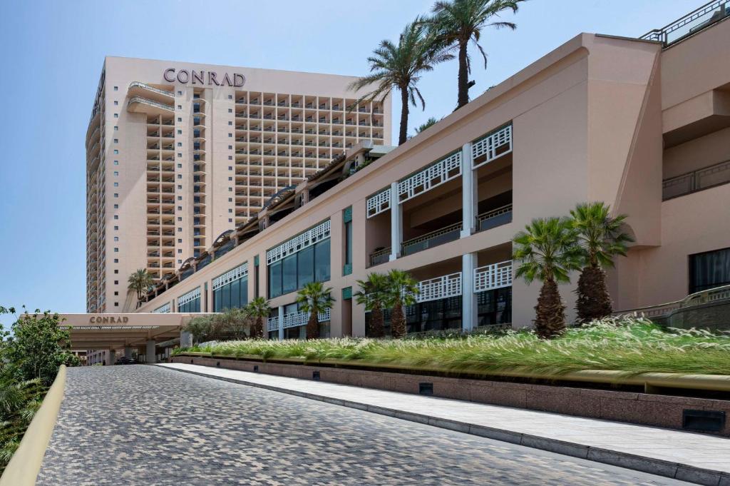 una calle frente a un edificio con palmeras en Conrad Cairo Hotel & Casino, en El Cairo